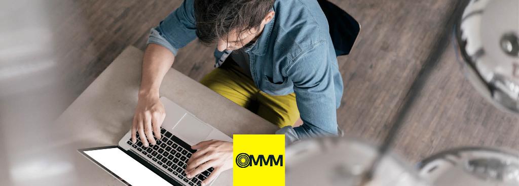 Ein Mann sitzt mit einem Laptop an einem Schreibtisch und tippt.