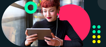 Eine rothaarige, junge Frau mit Ponyfrisur sitzt in einem Café und schaut auf ihr weißes Tablet. Sie liest den comdirect Newsletter.