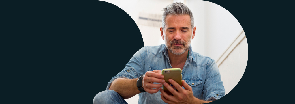 Ein Mann hält sein Handy in der Hand und schaut sich sein comdirect Depot an.