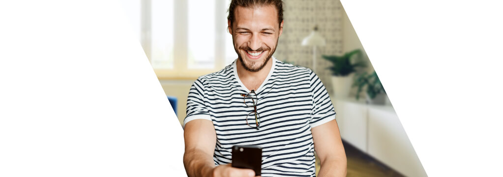 Ein junger Mann im Ringel-Shirt handelt auf seinem Smartphone mit ETFs.