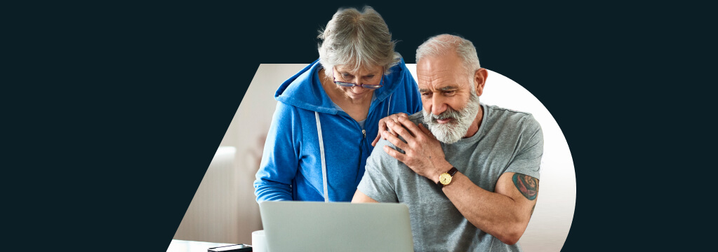 Eine ältere Frau mit Lesebrille steht hinter einem älteren Mann, der an einem Tisch sitzt. Ihre Hände berühren sich an seiner Schulter. Beide schauen gespannt auf das Ergebnis der Immobilienbewertung auf dem Notebook vor ihnen. Eine ältere Frau mit Lesebrille steht hinter einem älteren Mann, der an einem Tisch sitzt. Ihre Hände berühren sich an seiner Schulter. Beide schauen gespannt auf das Ergebnis der Immobilienbewertung auf dem Notebook vor ihnen.