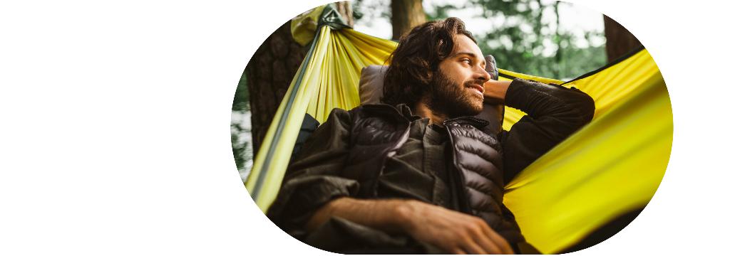 Ein junger Mann schaukelt entspannt in einer Hängematte.