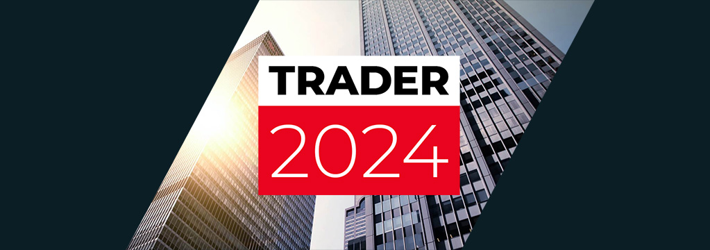 Sonnenbeschienene Hochhäuser ragen im Hintergrund in den Himmel. Im Vordergrund ist das Logo des Trader 2024 zu sehen.