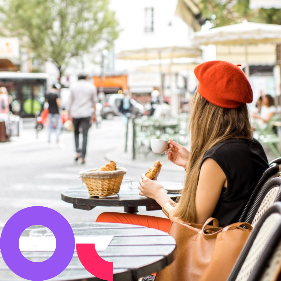 Eine junge Frau sitzt in einem Caf&eacute; und genie&szlig;t ein Croissant.