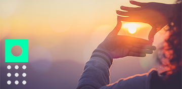 Eine Person bildet mit ihren H&auml;nden einen Rahmen um die untergehende Sonne.