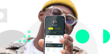 Ein Mann mit gelbem Beanie auf dem Kopf hält den Screen eines Smartphones nach vorne. Darauf ist sein Profil bei hi!stocks zu sehen.