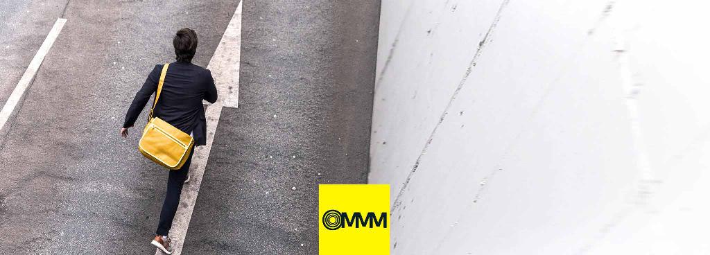 Ein Mann mit Anzug und gelber Tasche um die Schulter eilt eine Straße entlang.