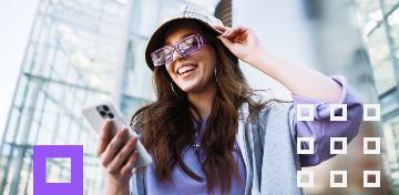 Eine junge Frau schaut gutgelaunt auf ihr Smartphone.