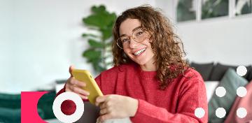 Eine junge Frau schaut gutgelaunt auf ihr Smartphone.