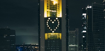Eine junge Frau mit Sonnenbrille steht lachend am Strand und macht ein Selfie.