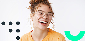 Lachendes Mädchen mit Brille und Locken trägt ein orangefarbenes T-Shirt. Auf dem Bild ist ein Störer mit dem Text „Bis 31.01.26“ zu sehen.