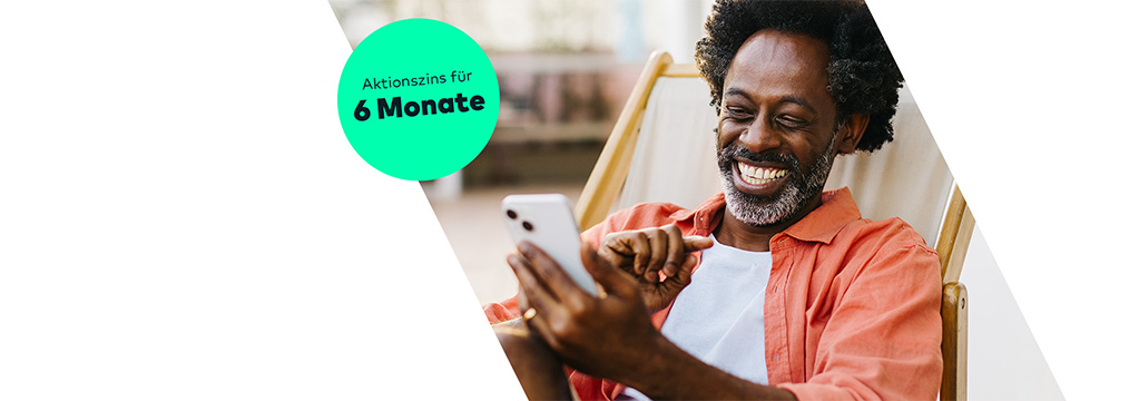 Ein lächelnder Mann liegt in einem Liegestuhl und schaut auf sein Handy. Links steht ein Störer "6 Monate 2% Zinsen p.a. Fußnote 1". Alle Fußnote werden unten erläutert.