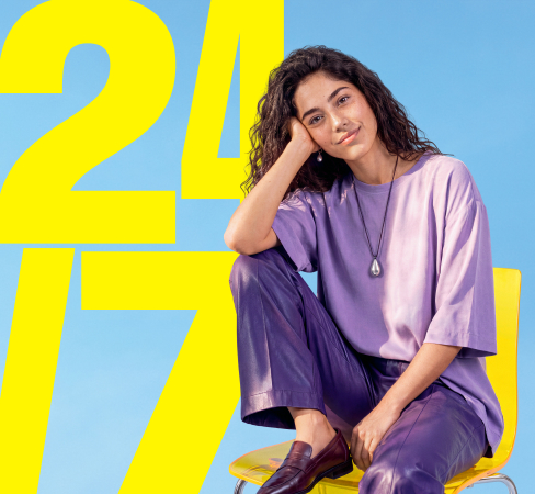 Auf einem Stuhl sitzt eine fr&ouml;hliche Frau. Im Hintergrund steht der Text "24/7".