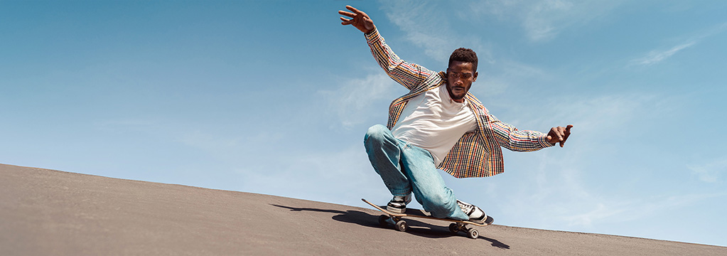 Mann f&auml;hrt Skateboard und h&auml;lt die Balance