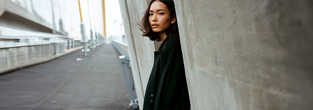 Frau lehnt ruhig an Betonwand und schaut entschlossen