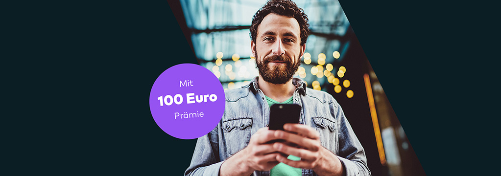 Mann mit Bart h&auml;lt ein Smartphone. Im Hintergrund sind Lichter zu sehen.