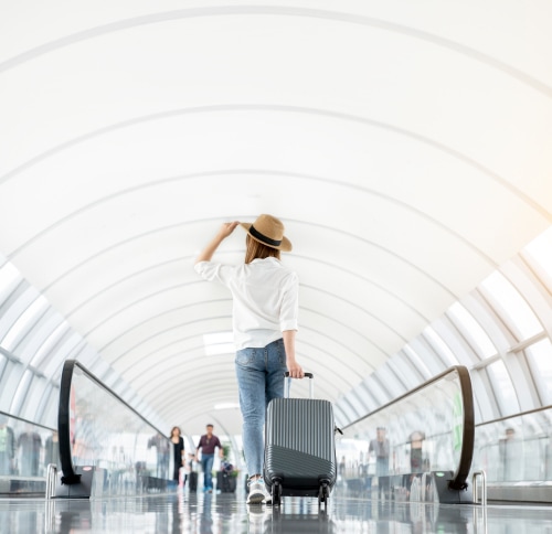 Visa-Debitkarte im Ausland: Frau mit Koffer am Flughafen