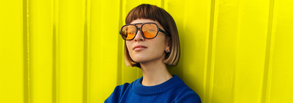 Eine junge Frau mit stylischer Sonnenbrille blickt l&auml;ssig.