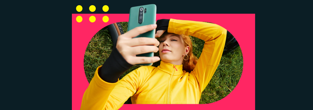 Eine junge Frau liegt im Gras und schaut auf ihr Smartphone. Sie freut sich über attraktive Zinsen auf dem Tagesgeldkonto.