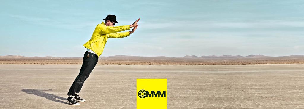 Ein Mann steht in einer Wüste und kippt mit erhobenen Armen nach vorne.