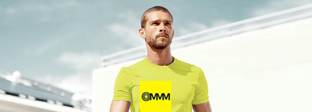 Ein junger Mann steht vor einem weißen Gebäude und schaut in die Ferne.