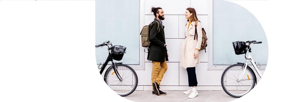 Ein junges Paar steht sich vor einer Wand gegenüber und lächelt sich an.