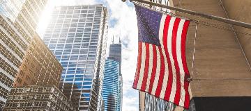Eine US-Flagge weht vor einem Wolkenkratzer.