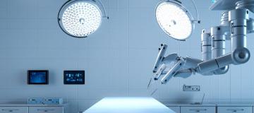 &Uuml;ber einem hell erleuchteten Operationstisch schwebt ein Operationsroboter.