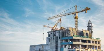 Auf einem Hochhaus-Rohbau stehen mehrere Braukr&auml;ne.