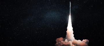 Eine Rakete startet mit einer wei&szlig;en Rauchwolke in das schwarze Weltall.