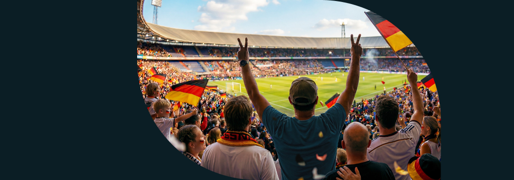 Fu&szlig;ballfans mit Deutschland-Flaggen jubeln in einem Stadion.
