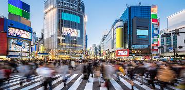 An einer Straßenkreuzung im Zentrum der Großstadt Tokio sind sehr viele Menschen unterwegs.
