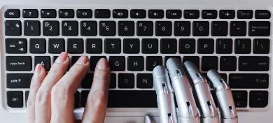 Eine Frauen- und eine Roboterhand tippen auf einer Tastatur.