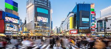 An einer Straßenkreuzung im Zentrum der Großstadt Tokio sind sehr viele Menschen unterwegs.