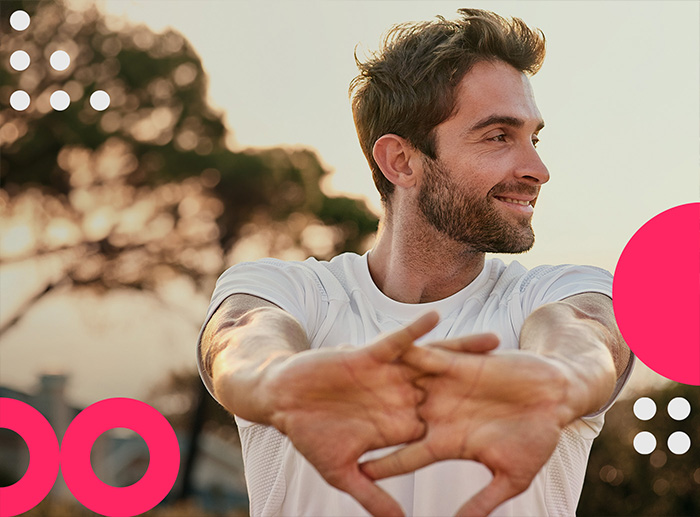 Ein junger Mann mit weißem Shirt und 3-Tage-Bart stretcht seine Arme. Er lächelt zufrieden, da er Festgeld bei comdirect anlegt.