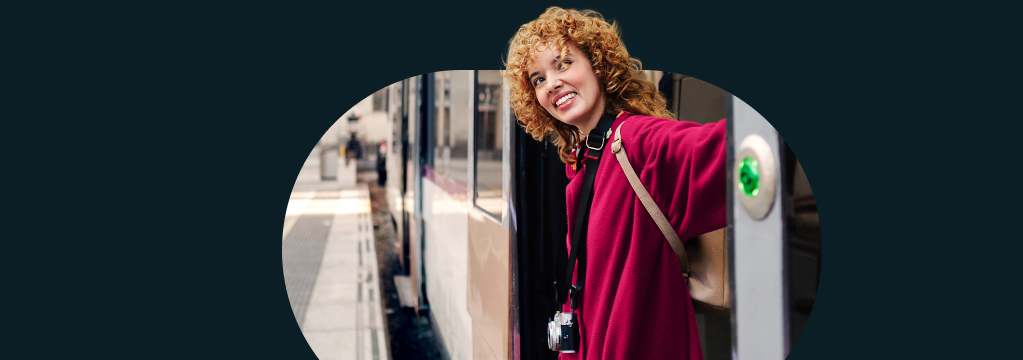Eine junge Frau steigt l&auml;chelnd an einem Bahnhof aus dem Zug. Auf einem St&ouml;rer steht "Der neue comdirect All World ETF ist da!"

 